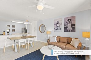 Un soggiorno moderno con zona pranzo, ventilatore a soffitto e opere d'arte alle pareti.