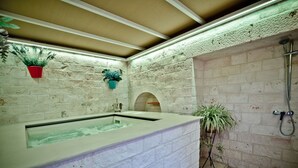 Un baño tipo spa con una bañera grande, ducha y pared de piedra.