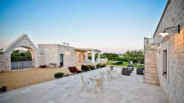 Un patio con muros de piedra, mobiliario exterior y vistas a un jardín.
