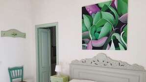 A bedroom with a bed, a chair, a nightstand, and a door. - Beachfront apartment with garden (Grottammare)