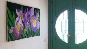 A painting of purple flowers on a wall next to a green door with a circular window. - Beachfront apartment with garden (Grottammare)