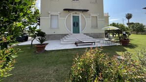 A building with a green door, white trim, and a staircase leading to the entrance. - Beachfront apartment with garden (Grottammare)
