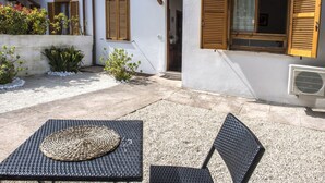 A patio with a table and chairs, a white building with wooden shutters, and a gravel ground. - N175 - Numana, two-room apartment with porch (Numana)