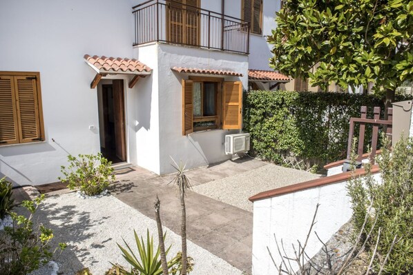 A two-story building with a white facade, wooden shutters, and a tiled roof.