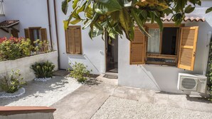 A courtyard with a white building, wooden shutters, a small garden, and an air conditioning unit. - N175 - Numana, two-room apartment with porch (Numana)