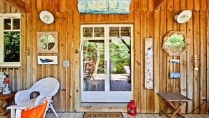 A wooden cabin with a glass door, wicker chairs, and nautical decorations. - Second line: pretty hut in the 44 Hectares (Lège-Cap-Ferret)