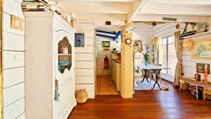 A cozy room with wooden floors, a dining table, and a kitchen area with a stove and cabinets. - Second line: pretty hut in the 44 Hectares (Lège-Cap-Ferret)
