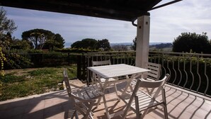 A covered patio with a table and chairs, overlooking a landscape with trees and hills. - N110 - Numana, villa with garden and sea view (Numana)