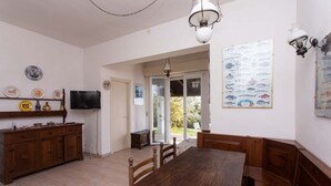 A dining area with a wooden table and benches, a television on the wall, and a fish-themed wall decoration. - N110 - Numana, villa with garden and sea view (Numana)