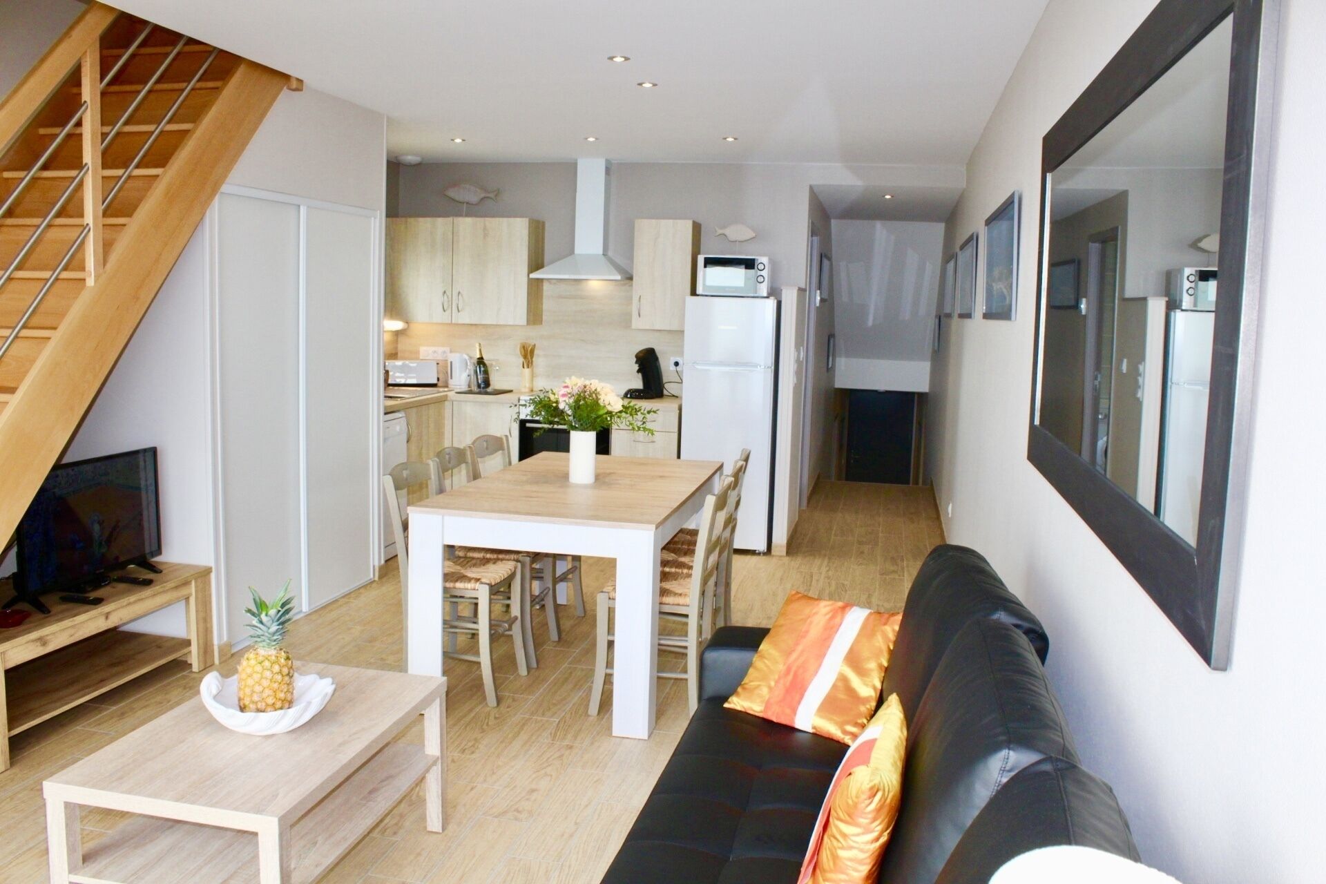 A compact living space with a dining area, kitchenette, and a sofa with cushions.