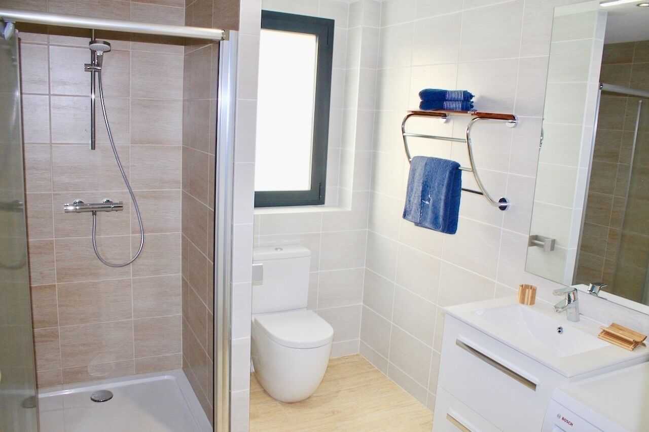 A modern bathroom with a shower, toilet, and sink.