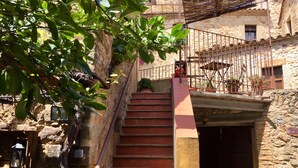 A stone staircase leading to a building with a metal railing and potted plants.