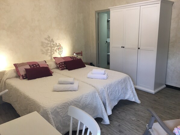 A bedroom with two beds, a wardrobe, and a chair.