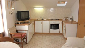 A compact kitchen with a television, stove, and sink.