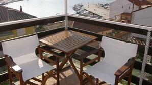A balcony with a table and chairs overlooking a marina with boats and a bridge.