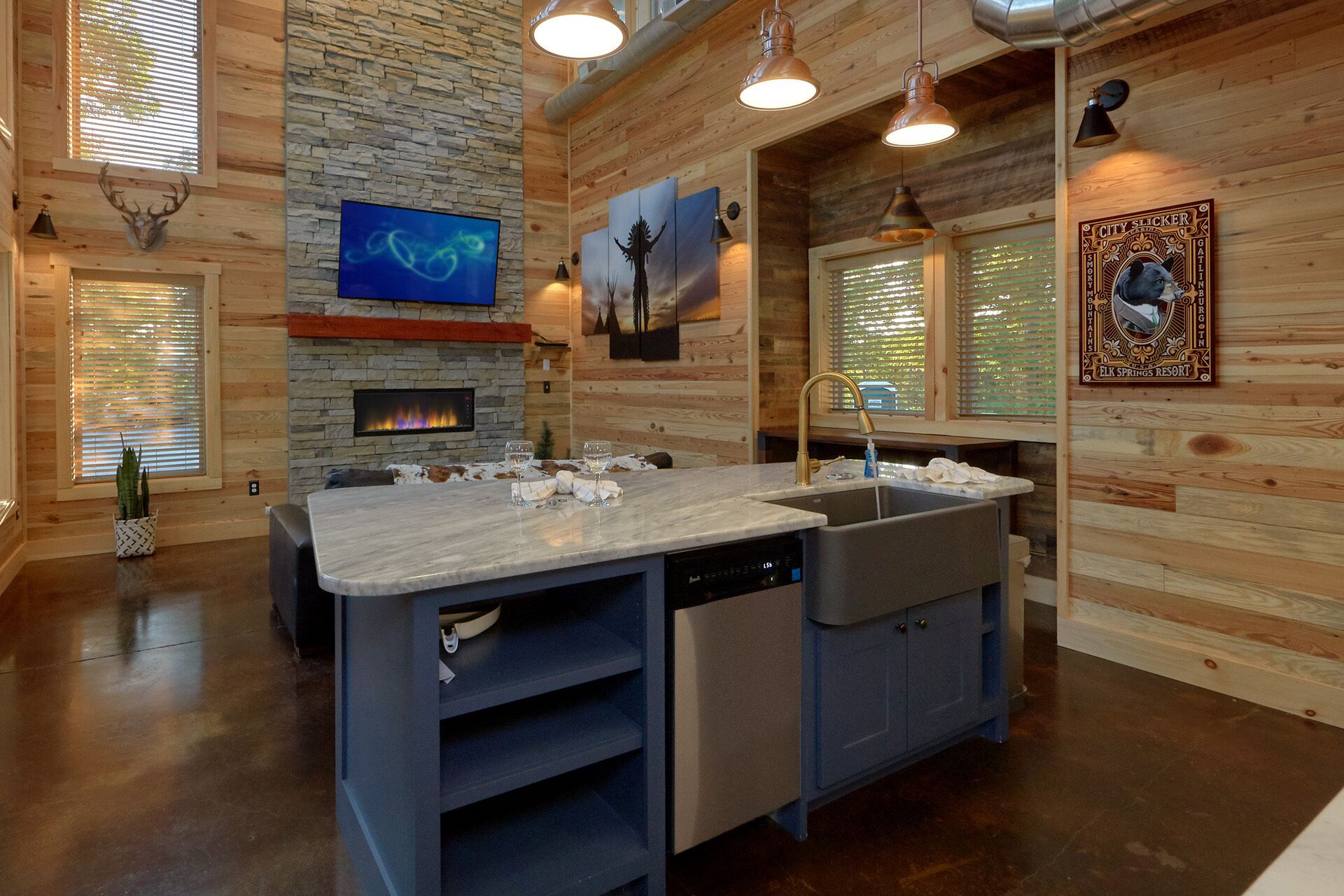A modern kitchen with a stone wall, a fireplace, and a large island with a sink and dishwasher.