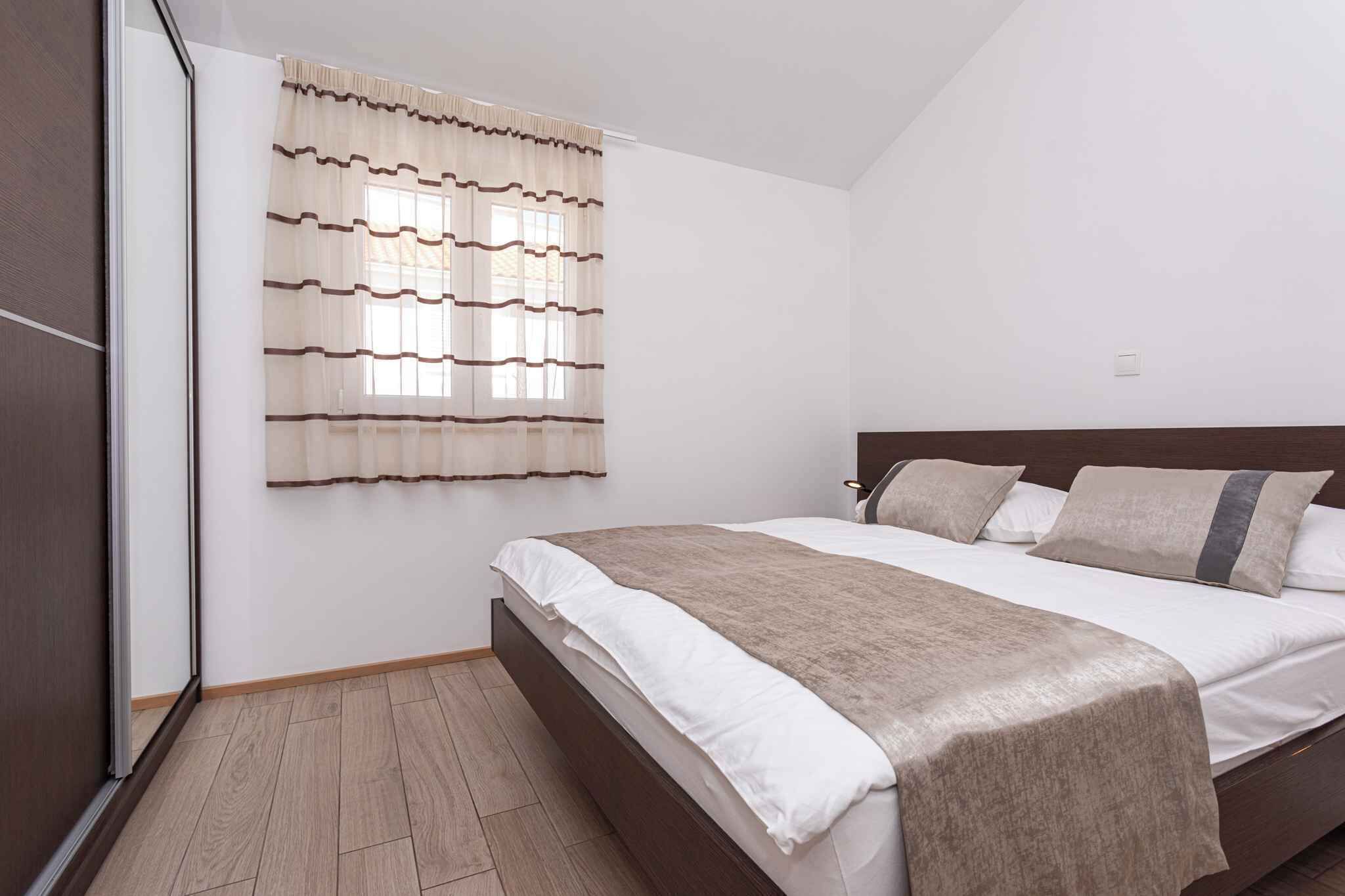 Een slaapkamer met een bed, een raam met gordijnen en een houten vloer.