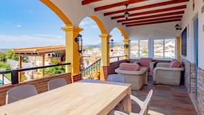 Ein überdachter Außenbereich mit Tisch und Stühlen sowie einer Pergola und Blick auf die Stadt.