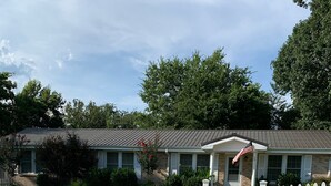 A two-story building with a white picket fence, a front porch, and an American flag.