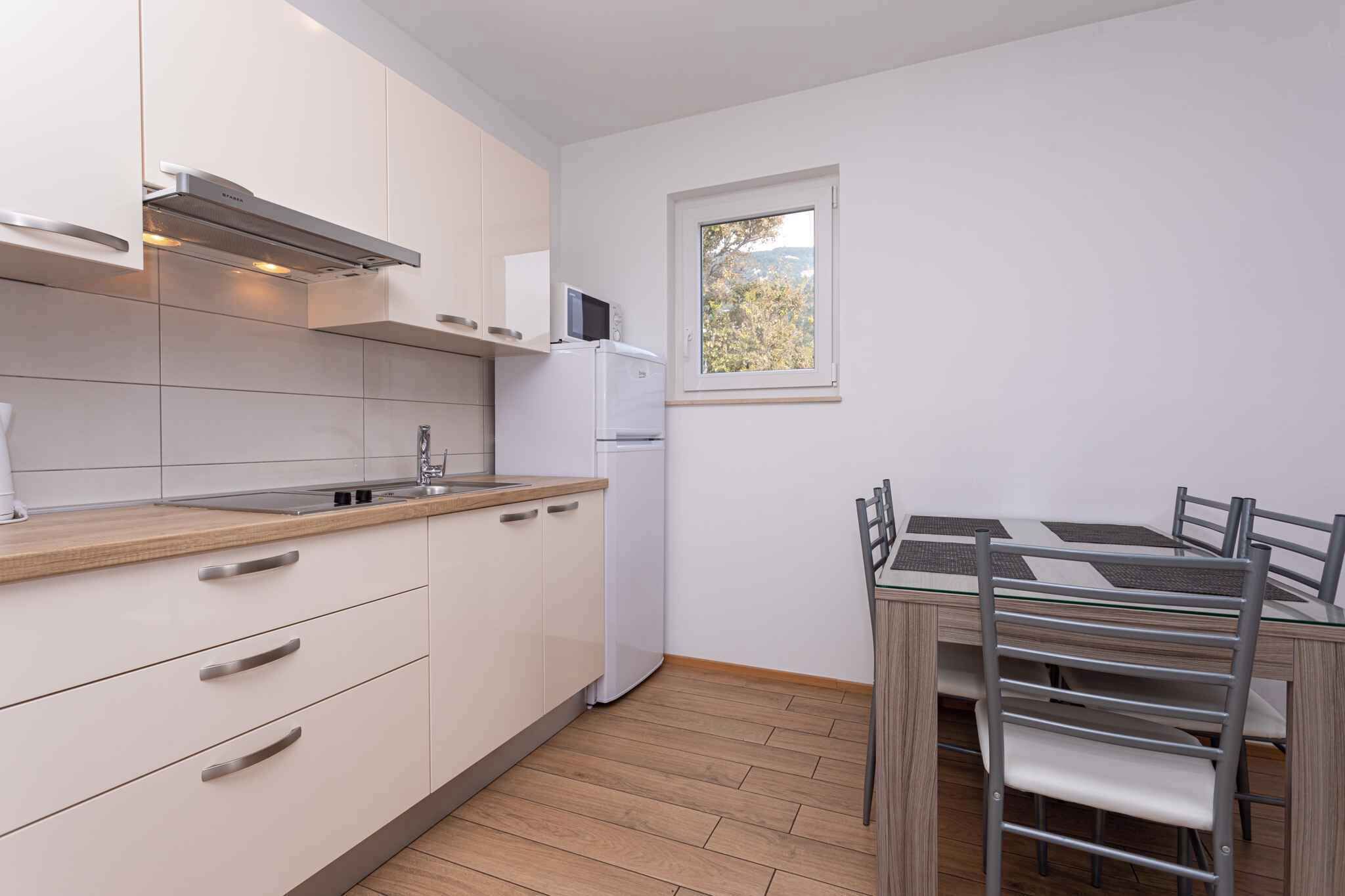 A compact kitchen with white cabinets, a built-in microwave, and a small refrigerator. There's a window providing natural light and a view of trees.