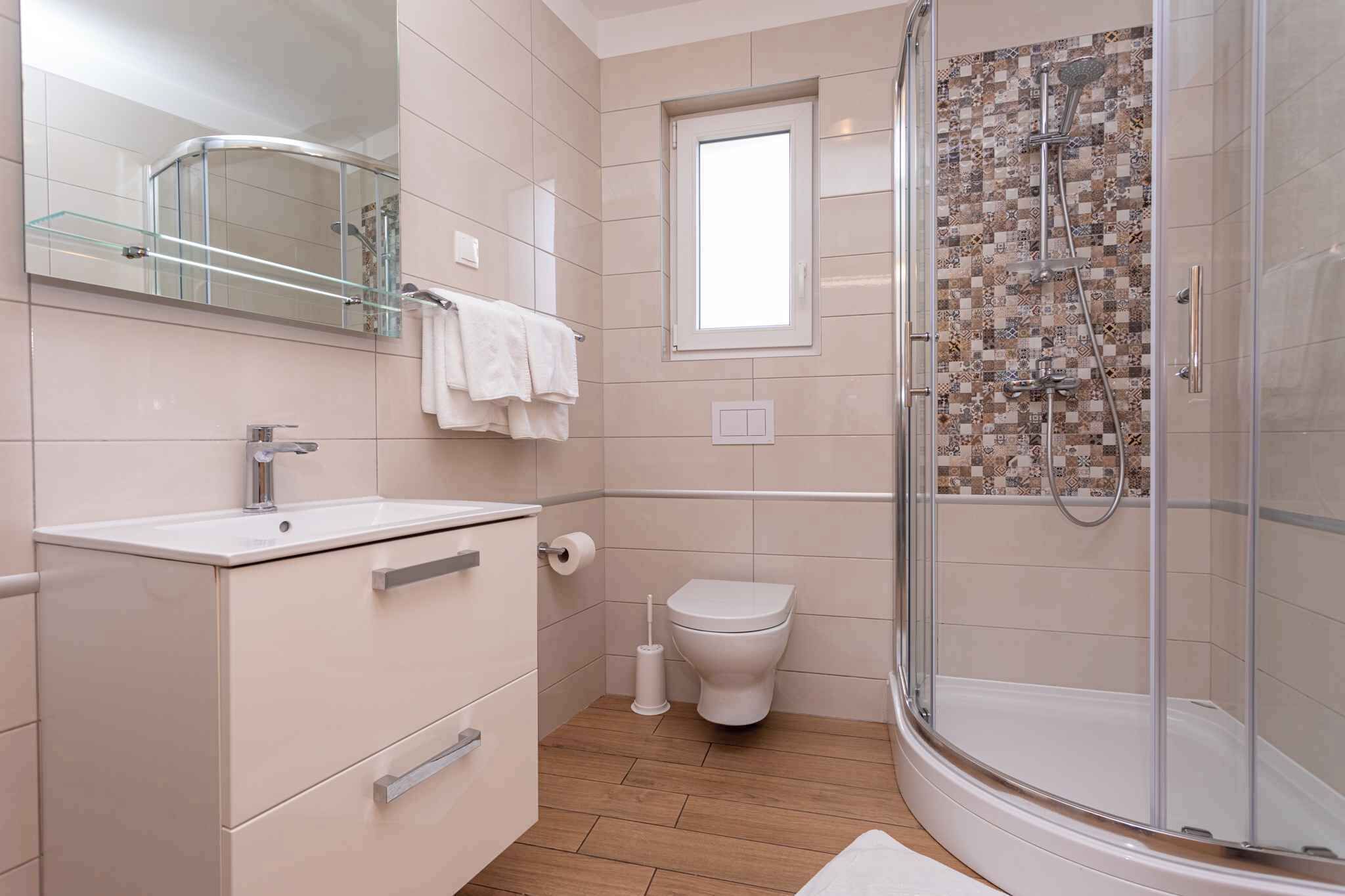 Une salle de bain moderne avec une douche à parois de verre, un lavabo blanc et des toilettes.
