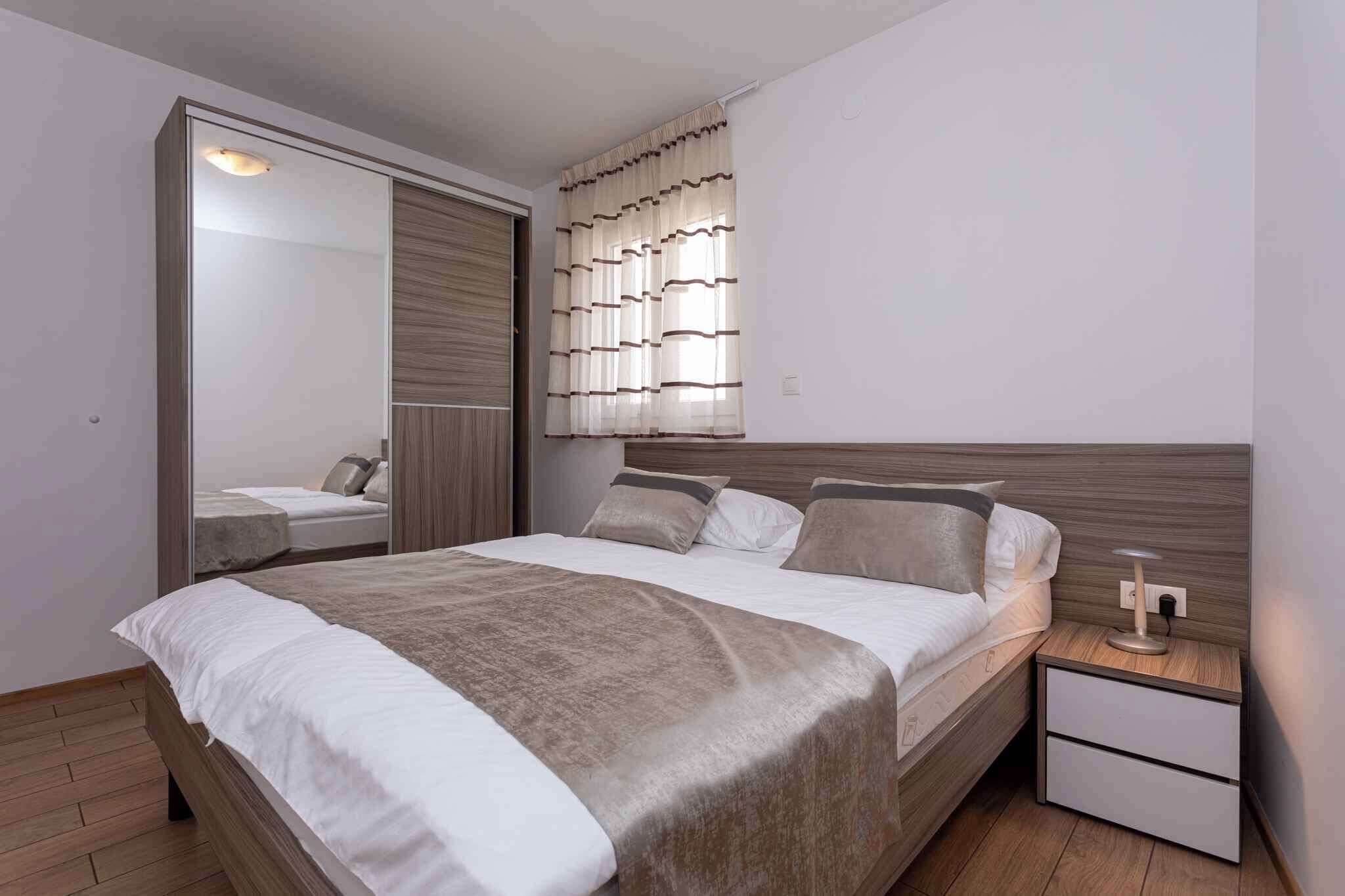 A modern bedroom with a bed, nightstands, a mirror, and a wardrobe.