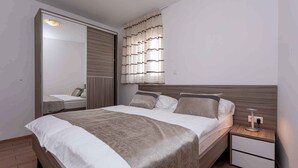 A modern bedroom with a bed, nightstands, a mirror, and a wardrobe.