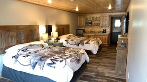 A cabin-style room with two beds, wooden floors, a kitchenette, and a TV mounted on the wall. - 406 Lodge (Gardiner)