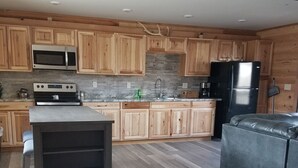 A modern kitchen with wooden cabinets, a stainless steel refrigerator, a microwave, and a built-in oven. - 406 Lodge (Gardiner)