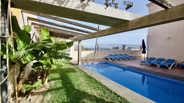 A swimming pool with lounge chairs and a pergola structure.