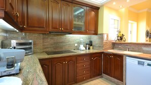 A kitchen with granite countertops, wooden cabinets, a dishwasher, and a coffee maker.
