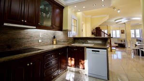 A spacious kitchen with dark wooden cabinets, a granite countertop, and a built-in dishwasher.