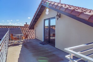 Ein Balkon mit Ziegeldach, einer Tür und einem kleinen Tisch mit Stühlen.