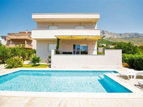 A modern two-story building with a swimming pool in front.