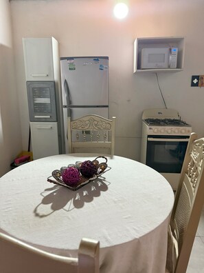 Une cuisine compacte équipée d’un réfrigérateur, d’un four à micro-ondes, d’une cuisinière et d’une table à manger agrémentée d’un élément décoratif central.