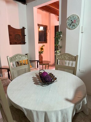 A dining area with a round table, two chairs, a wall clock, and a mirror.
