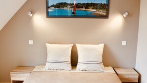 A bedroom with a bed, two pillows, a nightstand, and a framed picture of a sailboat on the wall. - BEACH 30 m, 3 bedrooms, 2 WC, Garden,Private Parking,electricity, water included (Barneville-Carteret)