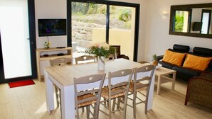 A dining area with a table and chairs, a sofa, and a television. - BEACH 30 m, 3 bedrooms, 2 WC, Garden,Private Parking,electricity, water included (Barneville-Carteret)