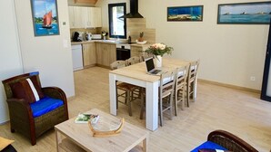 A modern living room with a dining area, kitchen, and a view of the sea. - BEACH 30 m, 3 bedrooms, 2 WC, Garden,Private Parking,electricity, water included (Barneville-Carteret)