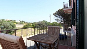 A balcony with a wooden table and chairs, overlooking a rural landscape with trees and a clear sky. - B&B treatment in La Maddalena, Sardinia (La Maddalena)