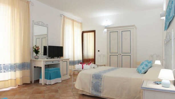 A hotel room with a bed, a desk with a computer, a TV, and a bathroom. - B&B treatment in La Maddalena, Sardinia (La Maddalena)