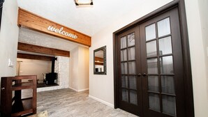 A hallway with a wooden bench, a fireplace, and a dark wooden door.