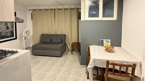 A compact living space with a kitchenette, a grey sofa, a dining table with chairs, and a small window. - 10 min walled city Single Aptment / Getsemani_301 (Cartagena)