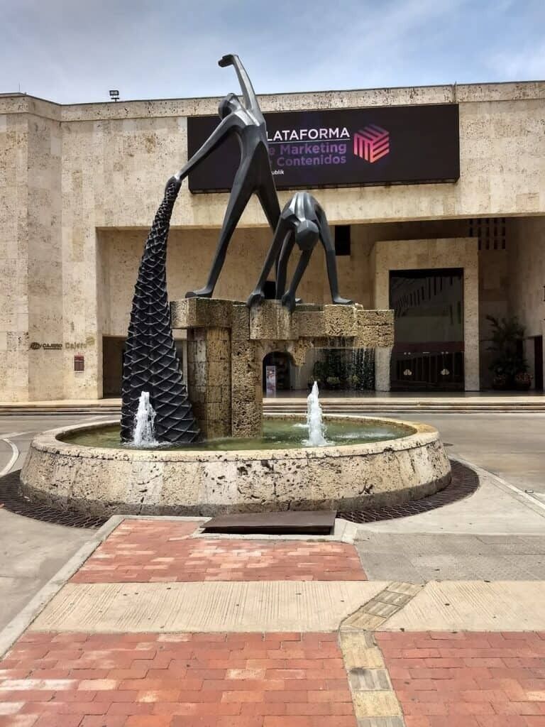 A fountain with a sculpture in front of a building with a sign reading 'DATAFORMA Marketing Contenidos.'