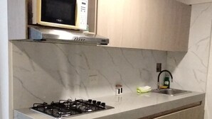 A kitchen with a gas stove, a microwave, and a sink. - 10 min walled city Single Aptment / Getsemani_301 (Cartagena)