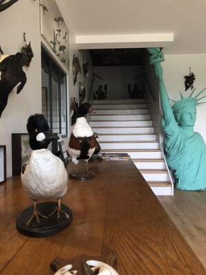 Una habitación con una mesa de madera que exhibe varias figuritas de pájaros y una estatua de la Estatua de la Libertad.