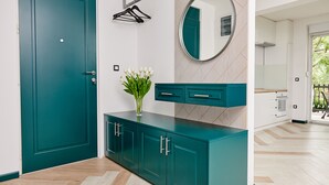 Ein turquoise gefärbtes Schränkchen mit Schubladen, einem Spiegel und einer Vase mit weißen Blumen.