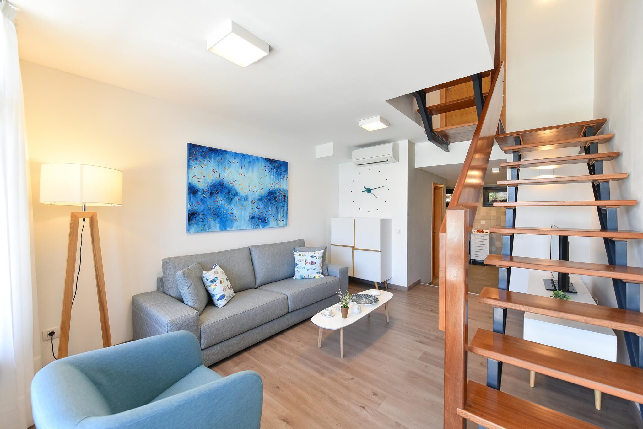 Een moderne woonkamer met een bank, een salontafel, een lamp en een trap.