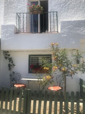 A white building with a balcony, a window with flowers, and a small table with chairs. - Holiday Flat With Sea Views (Mojácar)