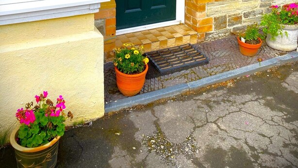 Una casa con puerta verde, paredes de piedra y una placa con el nombre 'HEDDFAN'.